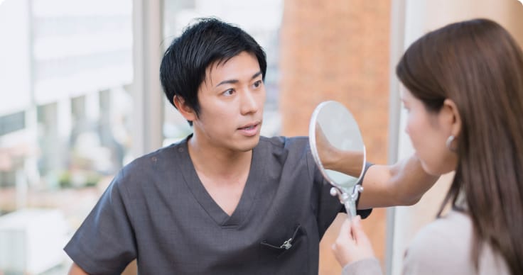 医師が患者と向き合い、鏡を使って悩みや希望を丁寧に確認するカウンセリングの様子を写したクリニック内の写真