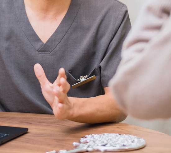 患者と向かい合って説明する医師の手元