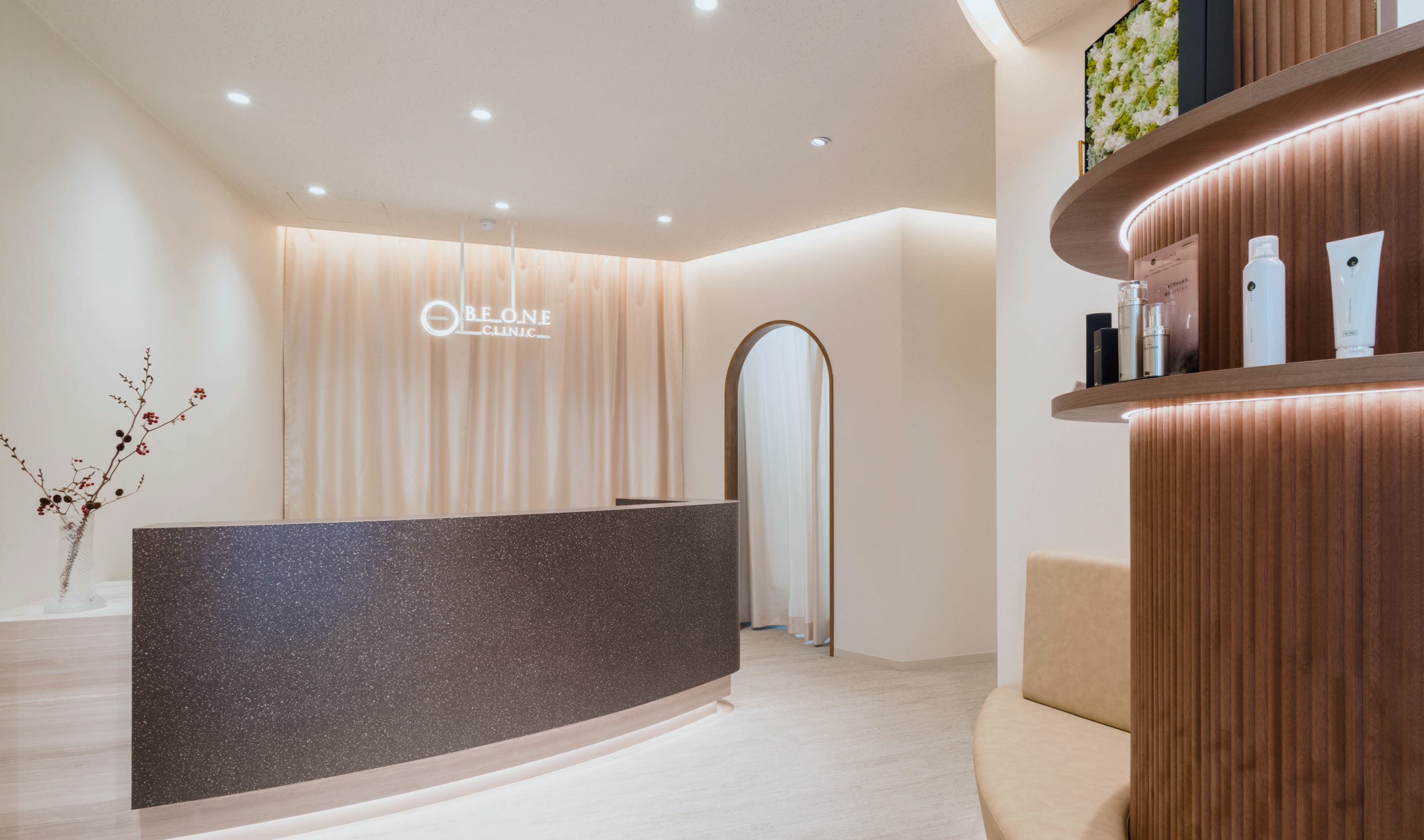 曲線を活かしたモダンな受付エリア。天井のダウンライトとアーチ型の入口が、清潔感と上質さを演出している